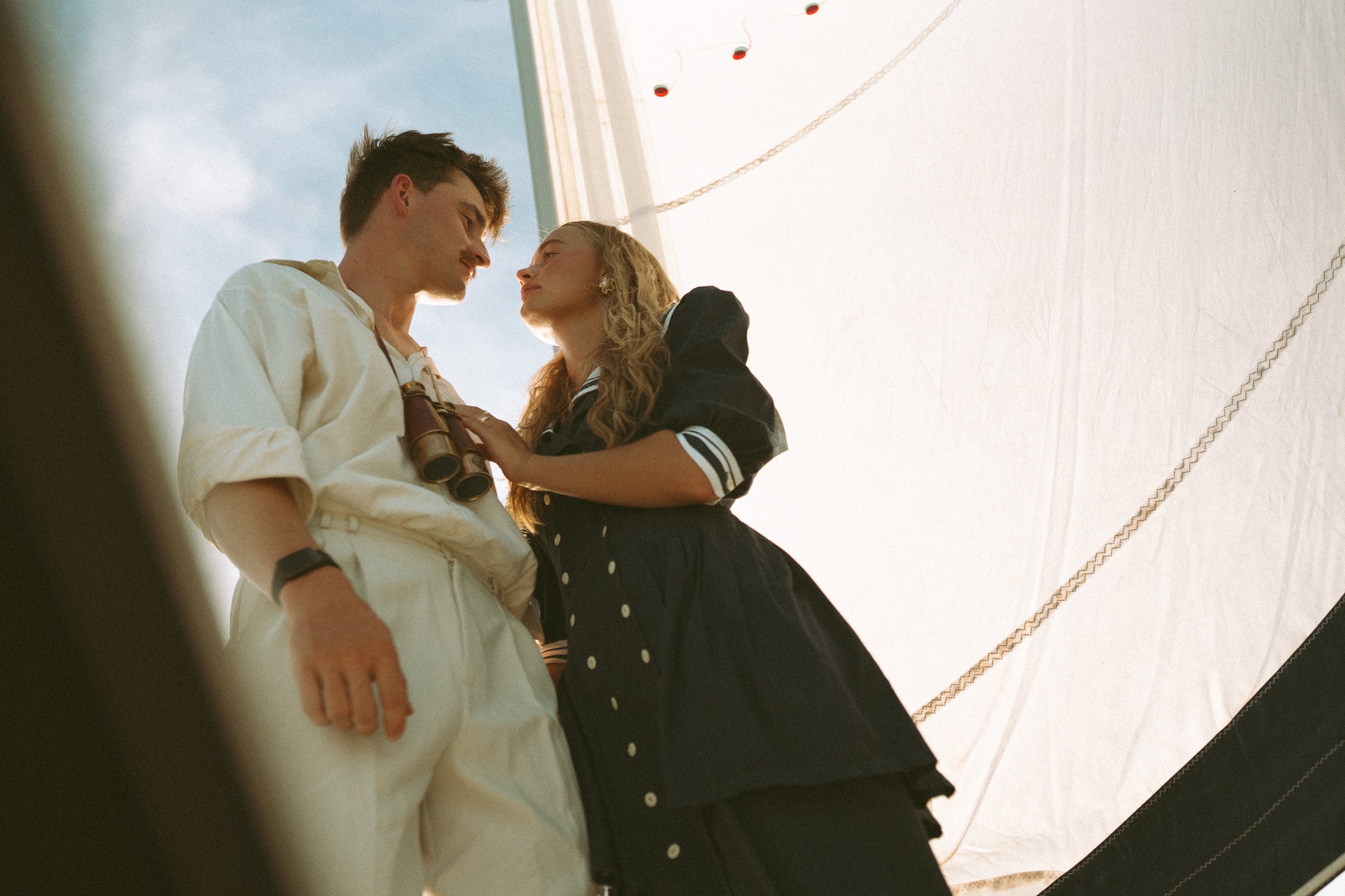A couple standing close beneath a sail on a boat