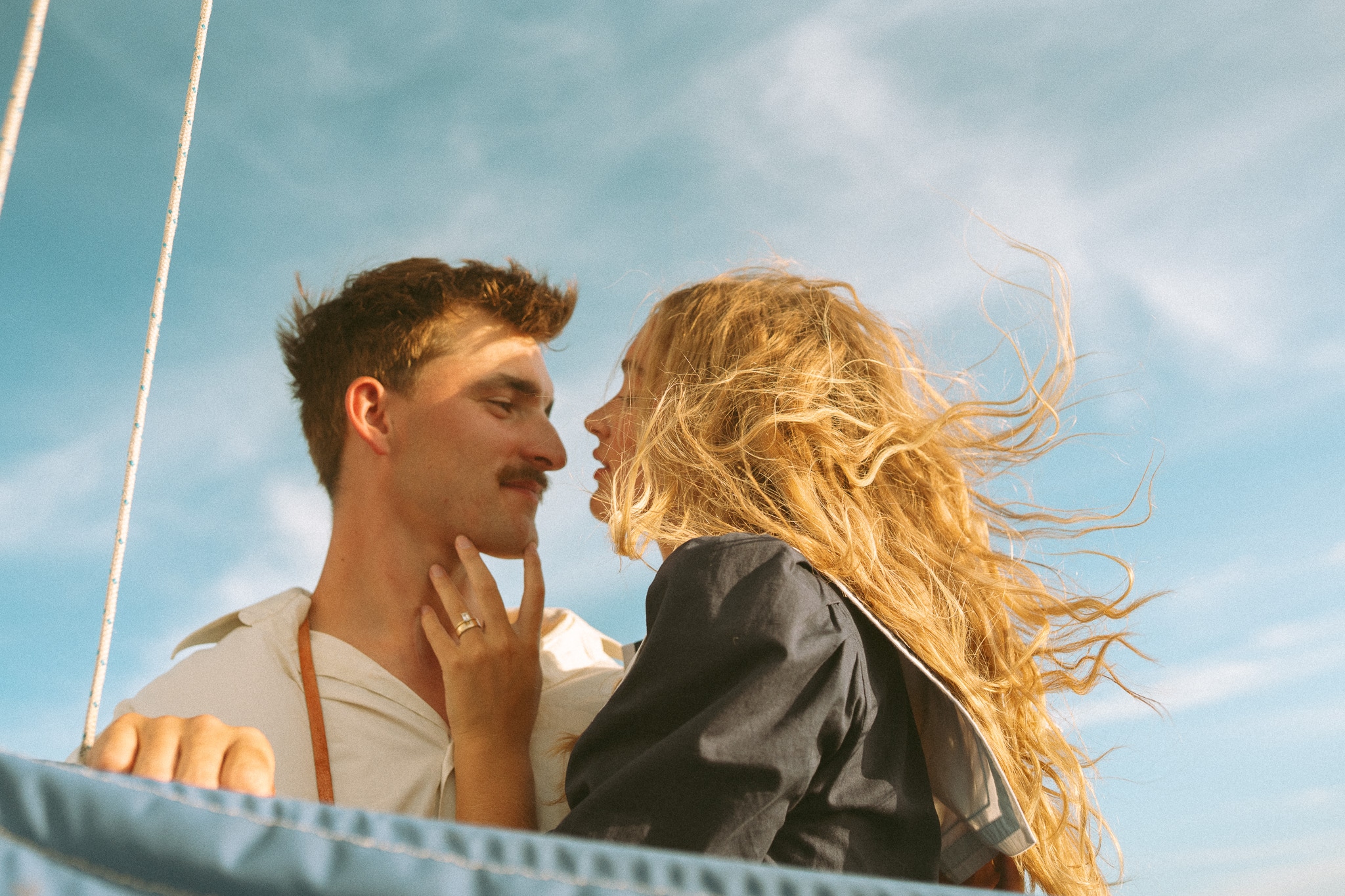A couple looking at each other against a blue sky on a boat